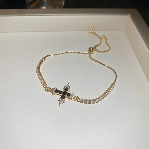 Detailaufnahme der goldenen Kreuz-Armkette mit schwarzem Stein und verstellbarem Verschluss