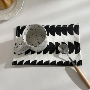 Detail of modern black and white geometric placemat on a minimalist breakfast table