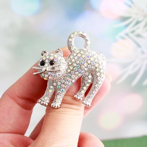 Sparkling silver cat brooch with colorful rhinestones held by hand for scale display