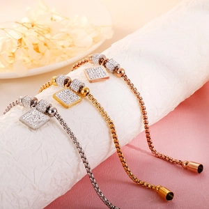 Détail de pendentifs carrés pavés sur des bracelets en argent, or et or rose à maille box