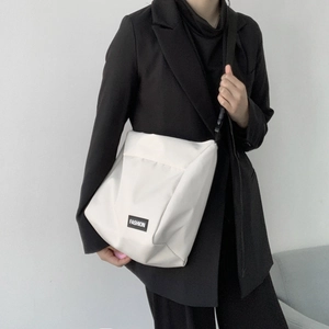 White large capacity canvas messenger bag shown on a model in a black suit