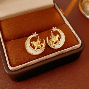 Detail view of Pegasus and moon earrings with white shell and star studs in velvet box
