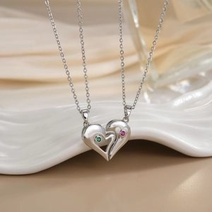 Macro shot of silver heart pendant necklaces with micro-set green and pink zircon stones