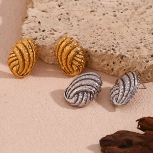 Detailed view of gold and silver hammered button earrings on a natural stone surface