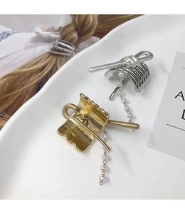 Detailed view of elegant gold and silver metal hair hooks with hanging pearl chain tassels