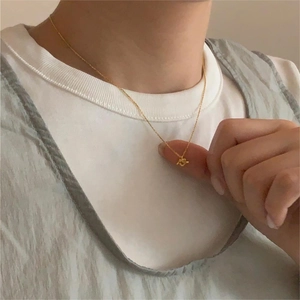 Detail of minimalist gold heart knot necklace worn by model for elegant everyday styling
