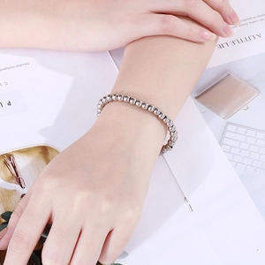 Dettaglio del bracciale minimalista con perline in argento lucido sul polso femminile