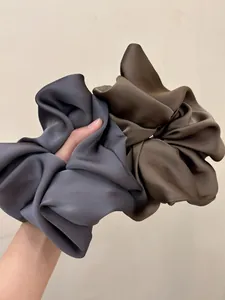 Detail of oversized satin scrunchies in smoky grey and coffee brown with a silky luster