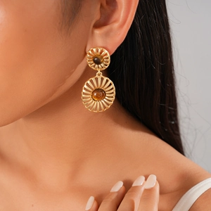 Detail of vintage gold sunburst earrings with amber stones on model's ear