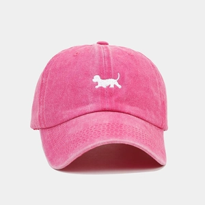 Detailed close-up of white puppy embroidery on a vintage washed pink baseball cap