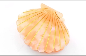 Detailed close-up of shell hair claw clip with orange marble texture and gold lines