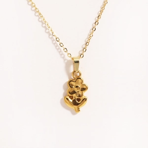 Close-up of 18K gold-plated flower pendant with leaf detail on a delicate chain
