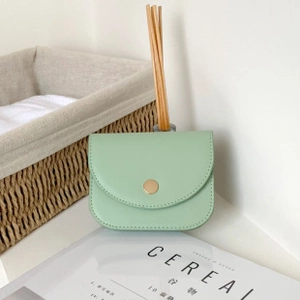 Close-up of mint green cross-pattern wallet with gold snap button on a white table