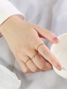 Detail von gedrehten 18K Gold-Titanringen und Zirkonia an einer Hand an einer Tasse