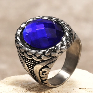 Macro detail of men's vintage ring featuring a faceted blue gemstone and woven texture