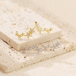 Close-up of star crawler earrings in gold and silver finish with sparkling zircons