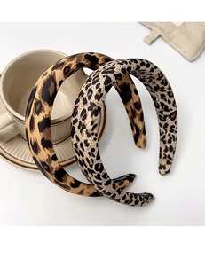 Detail of wide leopard print headbands with handmade logo on soft beige fabric