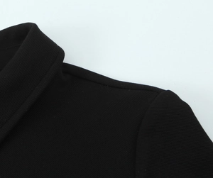 Gros plan d'une robe en crêpe noir montrant les coutures de l'encolure et la texture côtelée