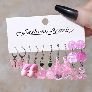 Close-up of pink resin earrings set featuring butterfly, mushroom and gummy bear designs