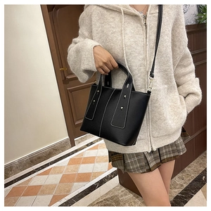 Black litchi leather tote bag with white contrast stitching and silver metal rivets