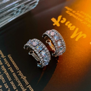 Détail macro de créoles argentées avec grands zircons carrés et micro-pavage de cristaux