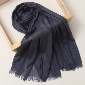 Detailed view of dark blue cotton linen scarf with soft fringe texture in a wooden frame