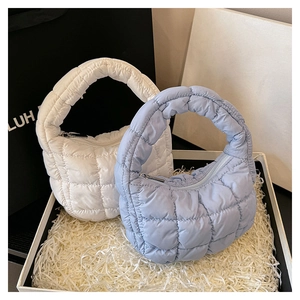 Macro view of beige and light blue quilted cloud handbags in a decorative gift box