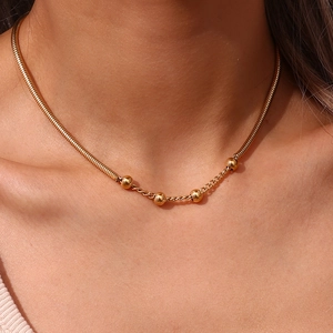 Detailed close-up of a gold-tone snake chain and round bead layered necklace for women