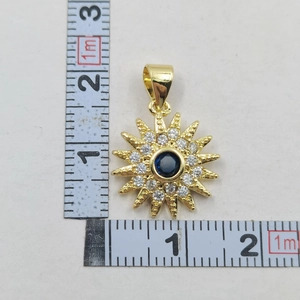 Detailed view of evil eye sun pendant with blue gemstone and dimensions shown by ruler