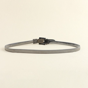 Macro detail of silver metal spring waist chain with textured black square buckle