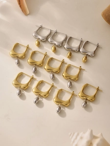 Detailed macro view of two-tone oval drop earrings on elegant beige stone surface