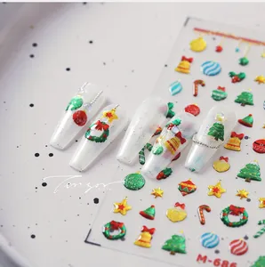 Detailed 3D Christmas nail stickers with trees and bells on white ceramic plate