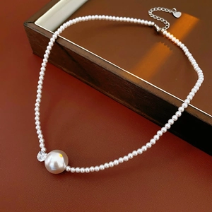 Dettaglio della collana di perle con perla grande e zircone su scatola di legno