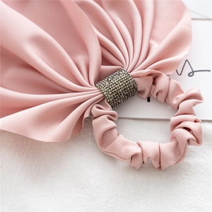 Detail of pink satin hair scrunchie with sparkling rhinestone band and silk texture