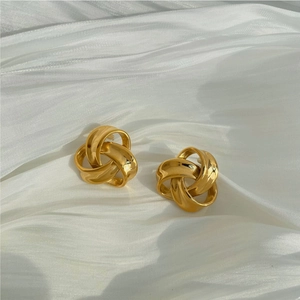 French vintage twisted gold knot earrings on white silk fabric, luxury metallic texture