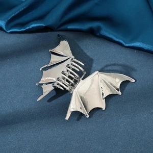 Silver metal bat wing hair claw clip for women on elegant blue satin fabric background