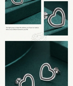 Detail of silver hollow heart stud earrings with dot edges on dark green background
