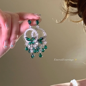 Détail de boucles d'oreilles papillon émeraude de luxe avec cristaux brillants à la main