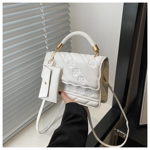 Close-up of white quilted handbag featuring woven handle, gold hardware and mini pouch