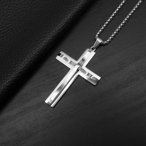 Macro shot of silver punk hip-hop layered cross pendant on a dark leather surface