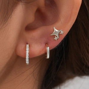 Close-up of three-piece silver earring set featuring a star stud and crystal hoop earrings