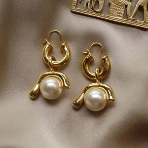 Exaggerated gold earrings with detachable natural pearls on champagne silk background