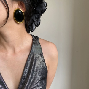 Close-up of retro oval stud earrings in black and gold on a fashion model