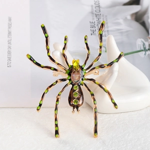 Gothic style large spider brooch with green stripes and yellow gems on ceramic hand stand
