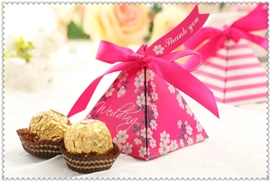 Close-up of pink pyramid wedding favor box with floral patterns and pink silk ribbon