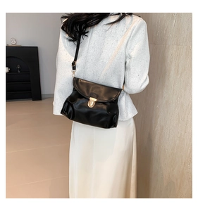 Detail of black pleated faux leather bag with elegant gold metal clasp and thin strap