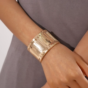 Detail of a wide gold minimalist irregular geometric open cuff bracelet on female wrist
