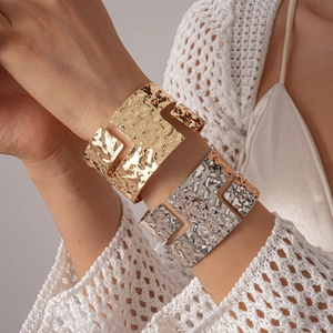Close-up of metallic wide open cuff bracelet featuring an irregular hammered lava texture
