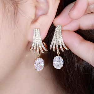 Elegant gold drop earrings with white zircon in a fanned design worn by a model