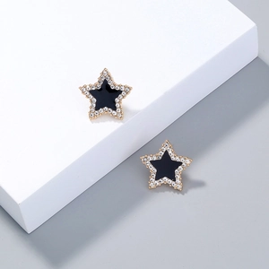 Detailed close-up of gold-plated star earrings with black enamel and white zircon inlay